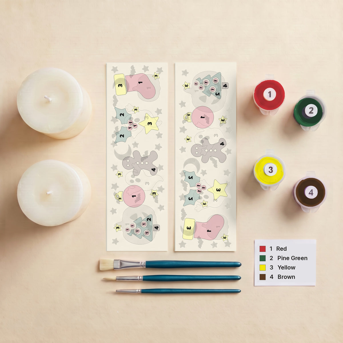 Everything in the Merry & Bright kit: two pillar candles, two numbered peel-off wraps, three brushes, four numbered pots of Opaque Candle Paint and the colour key