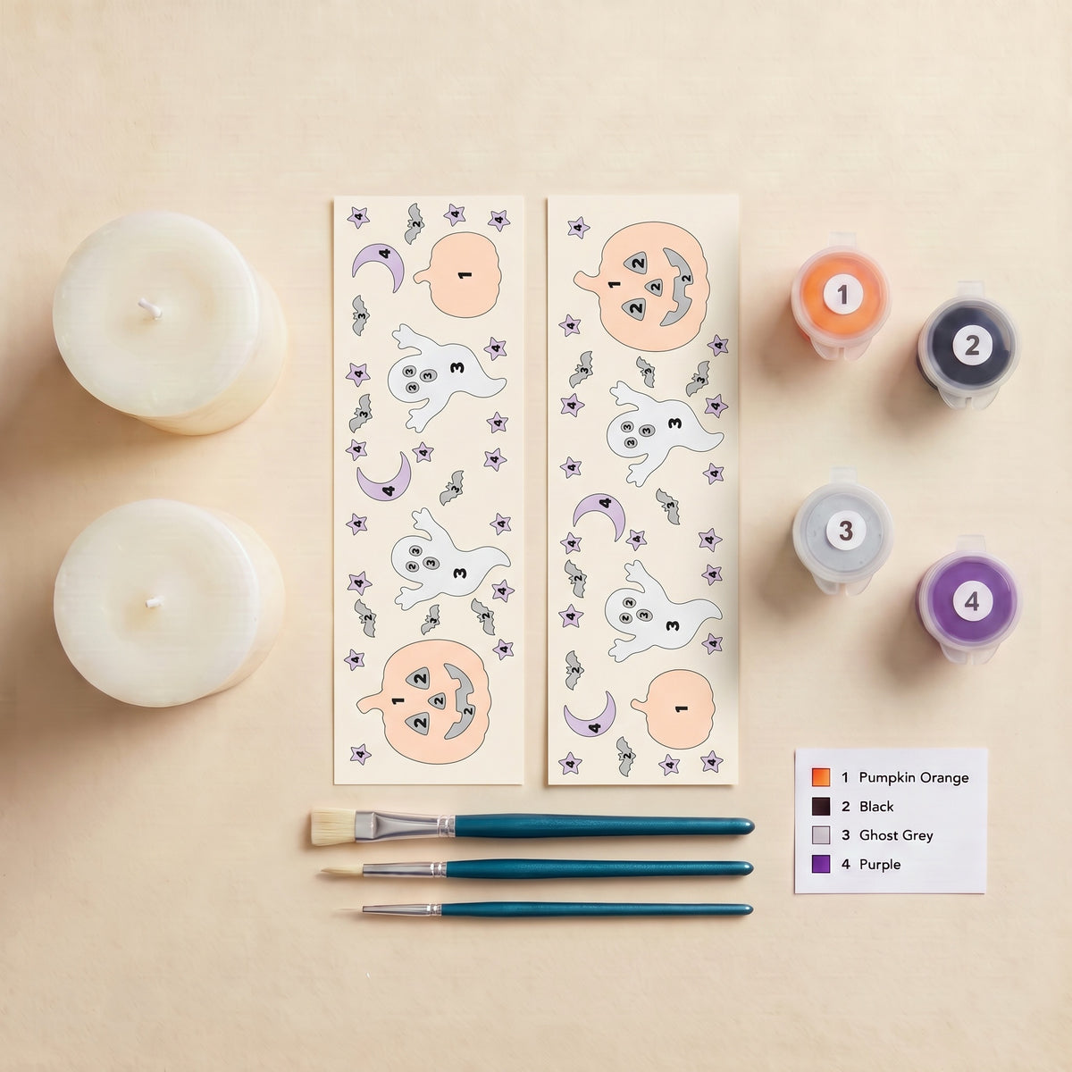 Everything in the Spooky Night kit: two pillar candles, two numbered peel-off wraps, three Brushible brushes, four numbered pots of Opaque Candle Paint and the colour key